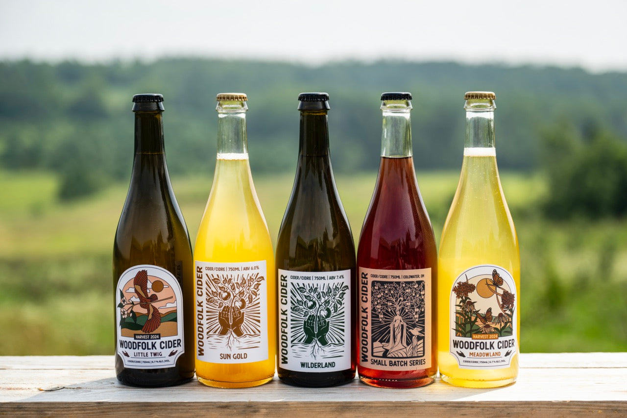 Five bottles of Woodfolk Cider with scenic background